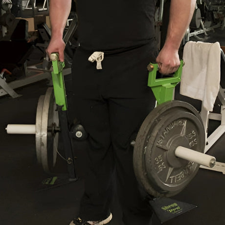 Person holding loaded farmer’s carry handles in a gym, ready to lift heavy weights.