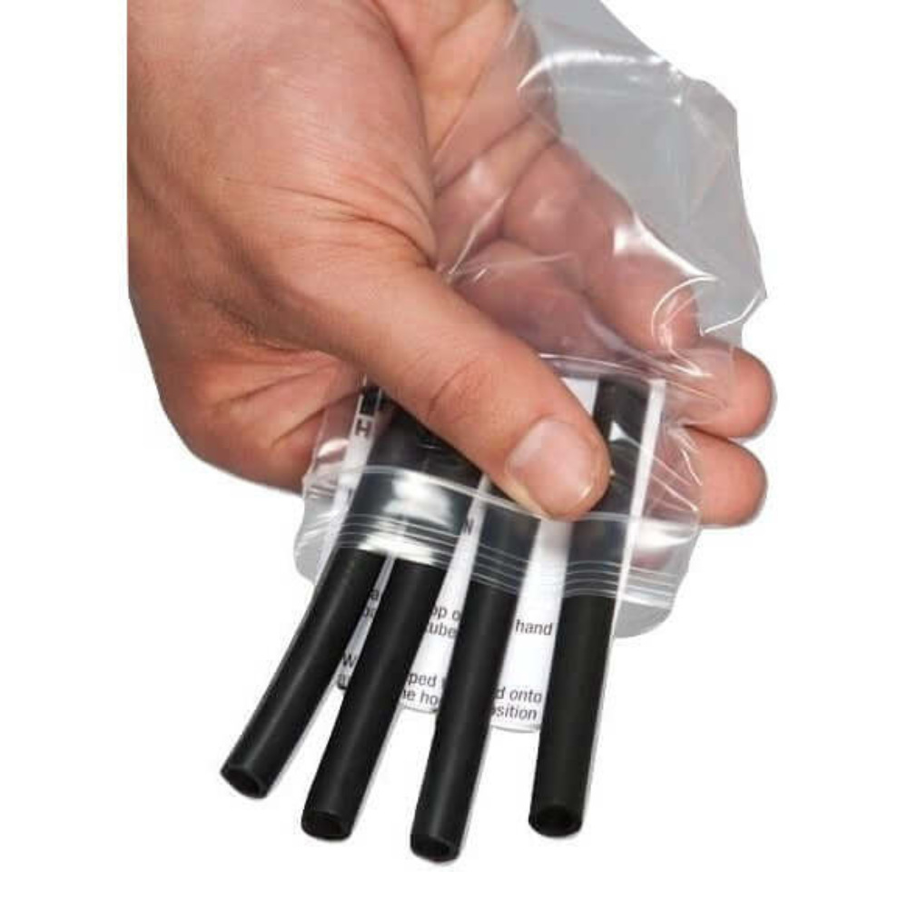 A hand holds a clear plastic bag with four black HAULIN HOOKS Gripper Tubes designed for barbell and dumbbell use.