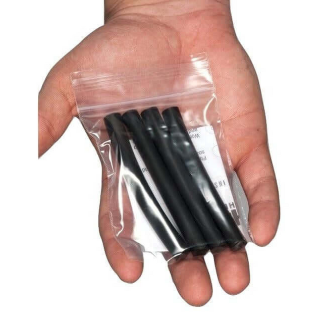 A hand holds a clear plastic bag containing HAULIN HOOKS Gripper Tubes, designed for easy use with barbells and dumbbells.