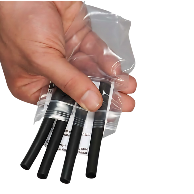 A hand holds a clear plastic bag with four black heat shrink tubes—perfect for securing HAULIN HOOKS 'Hanging Onlys' Weight Lifting Hooks. USA Made quality ensures lasting durability and reliability for your needs.