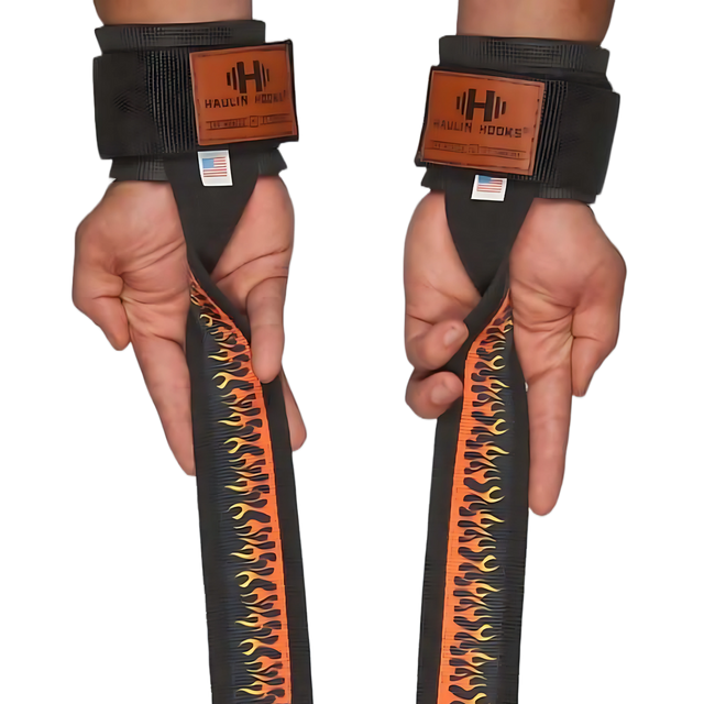 Two hands wear HAULIN HOOKS 'STRAPS 1000' black heavy-duty lifting straps with flame designs and labels, offering perfect grip and support for deadlifts.