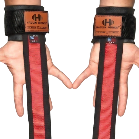 Two hands wearing black HAULIN HOOKS 'STRAPS 1000' heavy duty lifting straps with red accents and brown labels, ideal for extra grip during weightlifting wrist strap workouts.