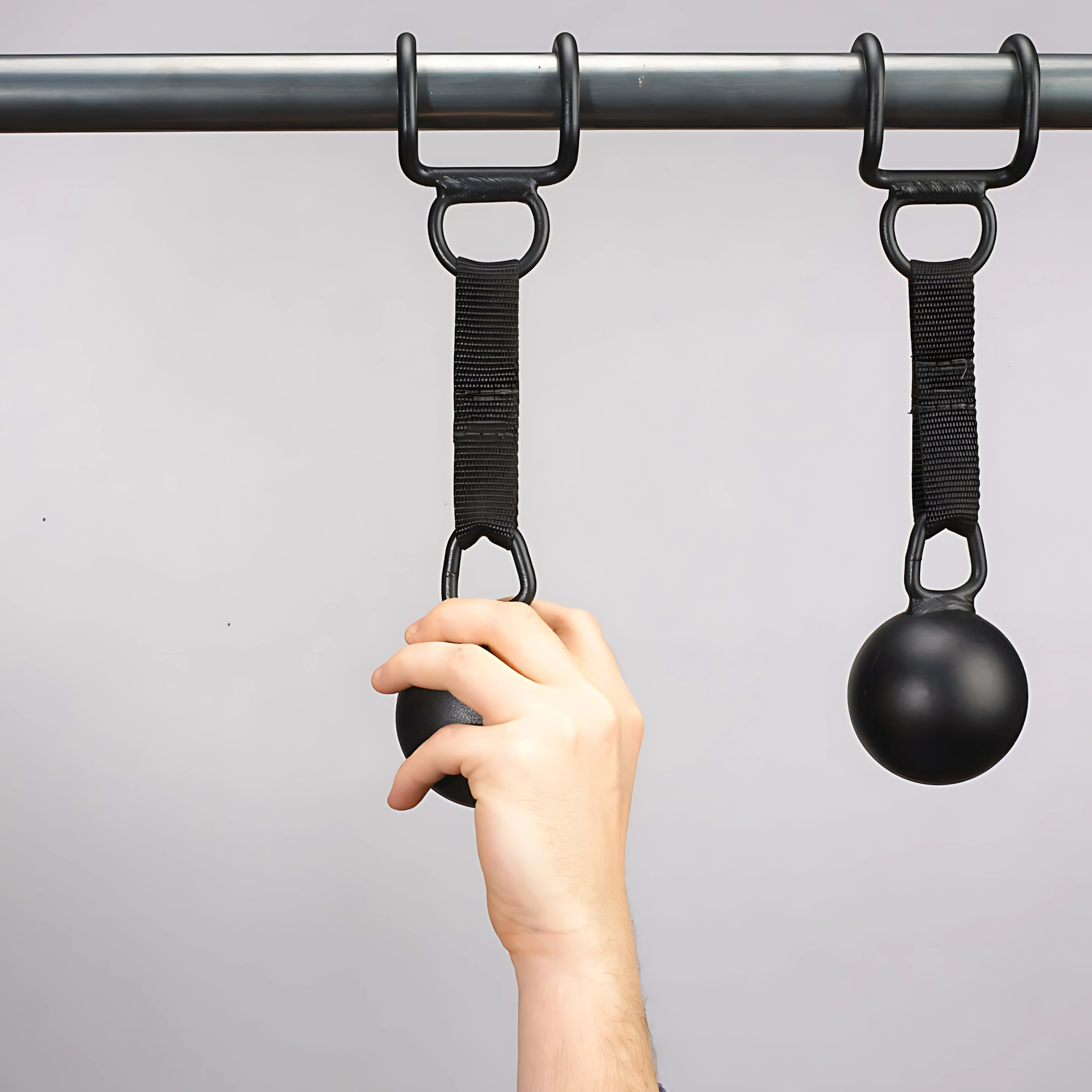 A hand grips a HOG LEGS 'Raging Boar' Pull-Up Grip, attached to a pull-up bar with a strap—perfect for enhancing grip strength during back workouts.
