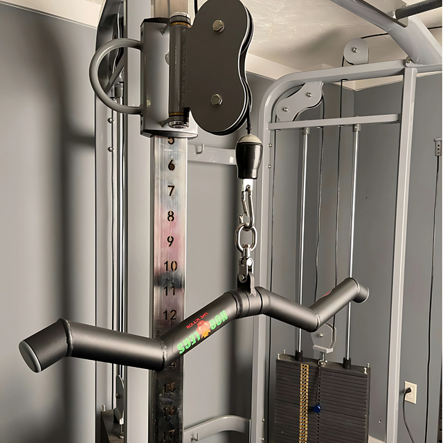 Close-up of the HOG LEGS 'SubPrimal' EZ Curl Bar / Triceps Workout Bar attached to a commercial cable machine, showcasing its versatile design and compatibility with a numbered weight stack for effective muscle training.