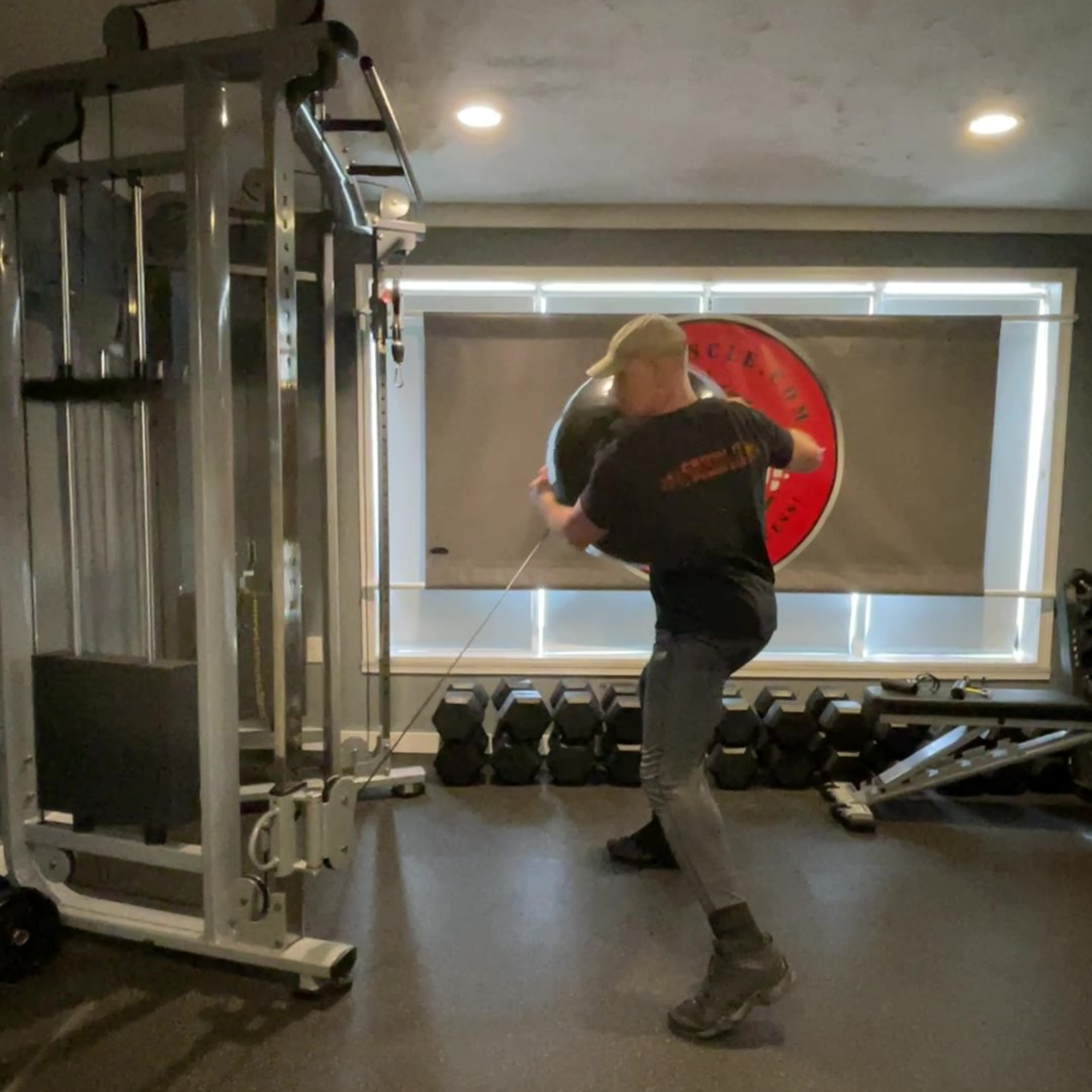 Using PHYSIO TWIST Swiss Ball Handle Straps for Cable Machine Core, a person performs a physio twist in the gym, swinging the cable with powerful core movement.