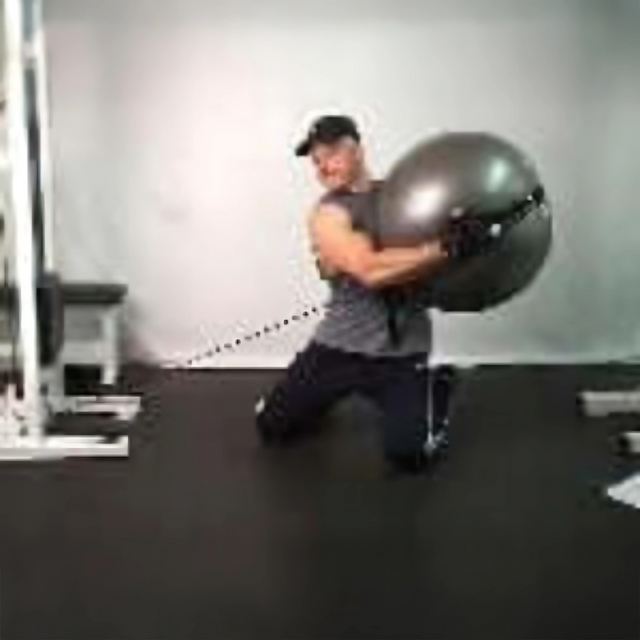Person kneeling on the gym floor, performing a core-strengthening Physio Twist using the PHYSIO TWIST Swiss Ball Handle Straps for Cable Machine Core—an explosive move targeting core muscles.