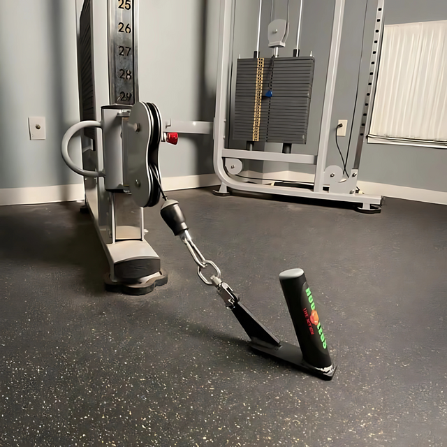 The HOG LEGS Jawbone Single Fat Grip Cable Machine Handle is attached to a cable machine, positioned on the gym floor in front of the weight stacks.