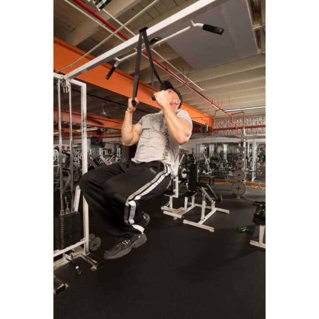 A man uses DELT-BELT Handle Straps for cable machine upright rows in a gym, surrounded by exercise equipment. Demonstrating strength and versatility, he contrasts his routine with precision targeted exercises.