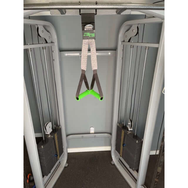 In the gym stands a gray cable machine with DELT-BELT Handle Straps, featuring green handles, as a versatile dumbbell alternative for muscle targeting and effective cable exercises.