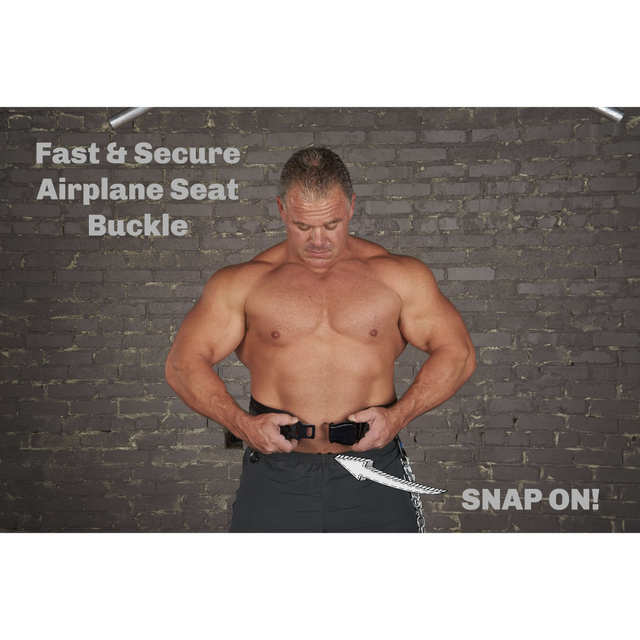 A muscular man demonstrates an airplane seat buckle against a brick wall, seamlessly incorporating its features—similar to the precision required for loading an E-Z DIP BELT with Chain or mastering weighted triceps dips.