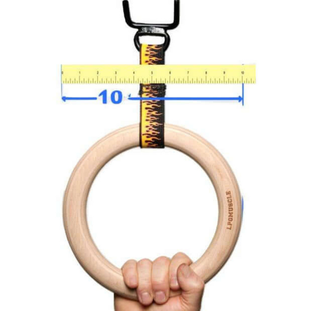 A hand holds a wooden gymnastics ring with a flame-patterned strap, showcasing commercial-grade USA craftsmanship, and a ruler marks 10 inches above. Product: GYMNASTICS RINGS Pull up Handles Roman Ring Pull Up Grips.