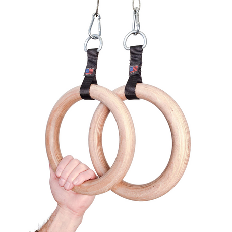 A hand grips two Gymnastic Rings Cable Machine Handles with black straps and metal hooks, highlighting the strength and precision required for a perfect Roman Ring workout.