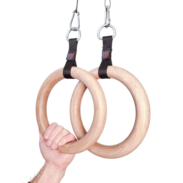 A hand grips two Gymnastic Rings Cable Machine Handles with black straps and metal hooks, highlighting the strength and precision required for a perfect Roman Ring workout.