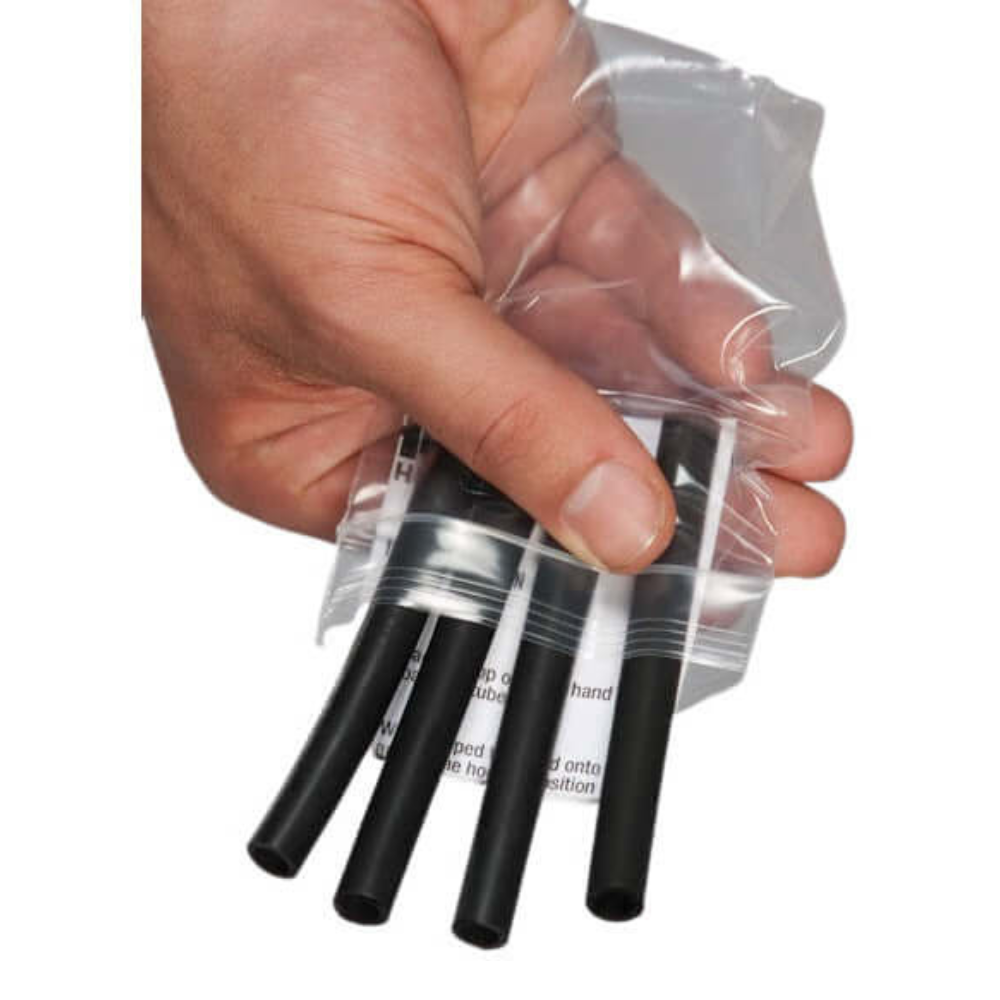 A hand effortlessly secures a clear plastic bag with a thumbless grip, showing four small HAULIN HOOKS Wide Glide 4.5" Weightlifting Hooks inside.