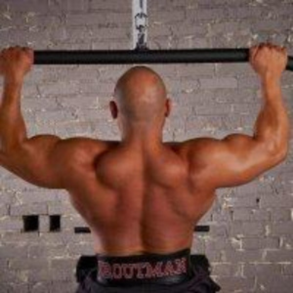 A man performs a pull-up with the HOG LEGS 48" FAT Lat Pulldown Straight Bar against a gray brick wall, emphasizing his wide back and muscular arms, perfectly showcasing the muscle-stimulating exercise.