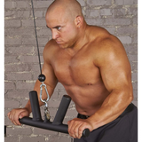 A man is intensely focused as he works out with the HOG LEGS 'Arm Yourself' Cable Machine Attachments Set, gripping the FAT 1 3/4″ round welded steel handles against a gray brick wall background.