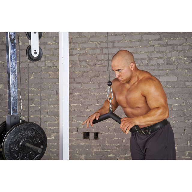 A man exercises in the gym with a cable machine against a brick wall, using the HOG LEGS 'Arm Yourself' Cable Machine Attachments Set's FAT 1 3/4" round welded steel grip for optimal performance.
