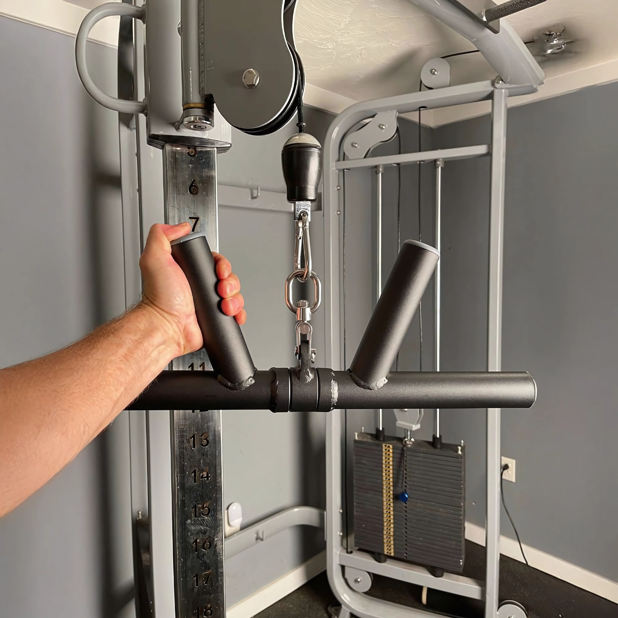 A hand grips the HOG LEGS 'Boar Tusk' Fat Grip Curling Bar attached to a cable machine, targeting biceps and forearms during triceps cable exercises.