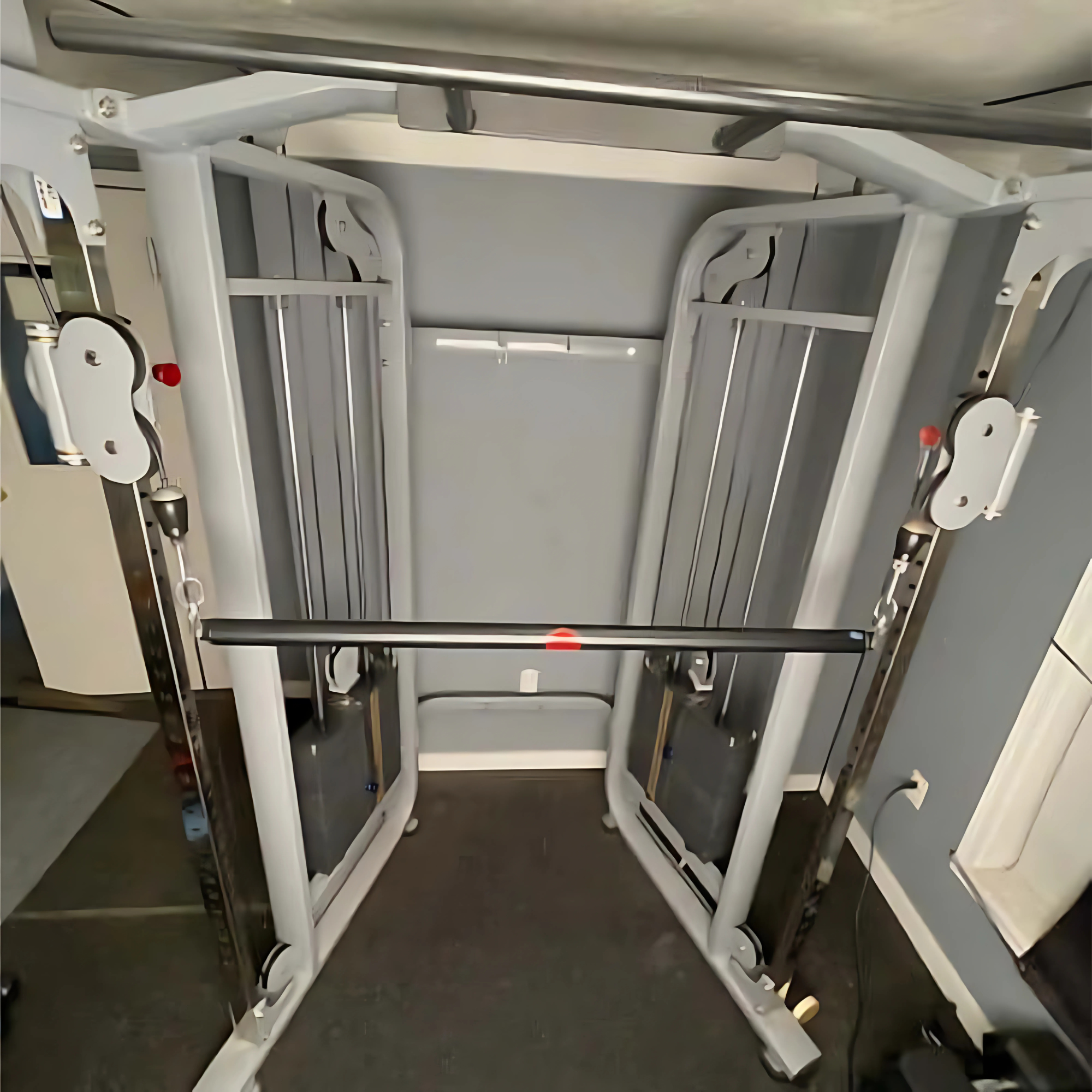 The HOG LEGS Dual Cable Bar Cable Attachments for Gym in a home gym with gray walls and black flooring, featuring a dual pulley system for versatile workouts.