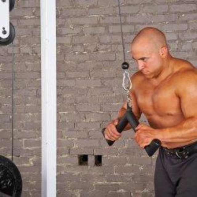 A man is focused on his workout, sculpting his biceps and triceps using the HOG LEGS 'Feral Hog' Arm Workouts with Cables Bar set against a striking brick wall backdrop in the gym.