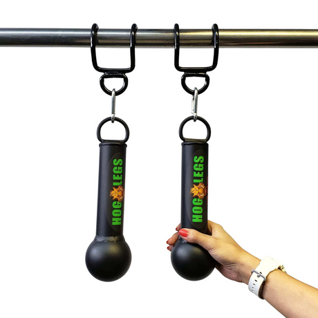 A hand with red nails holds the "HOG LEGS 'Fist Full' Pullup Handles & Tricep Attachment," black rubber grips designed to boost grip strength. Perfect for enhancing pull-ups, these innovative ball grips hang securely from the bar.