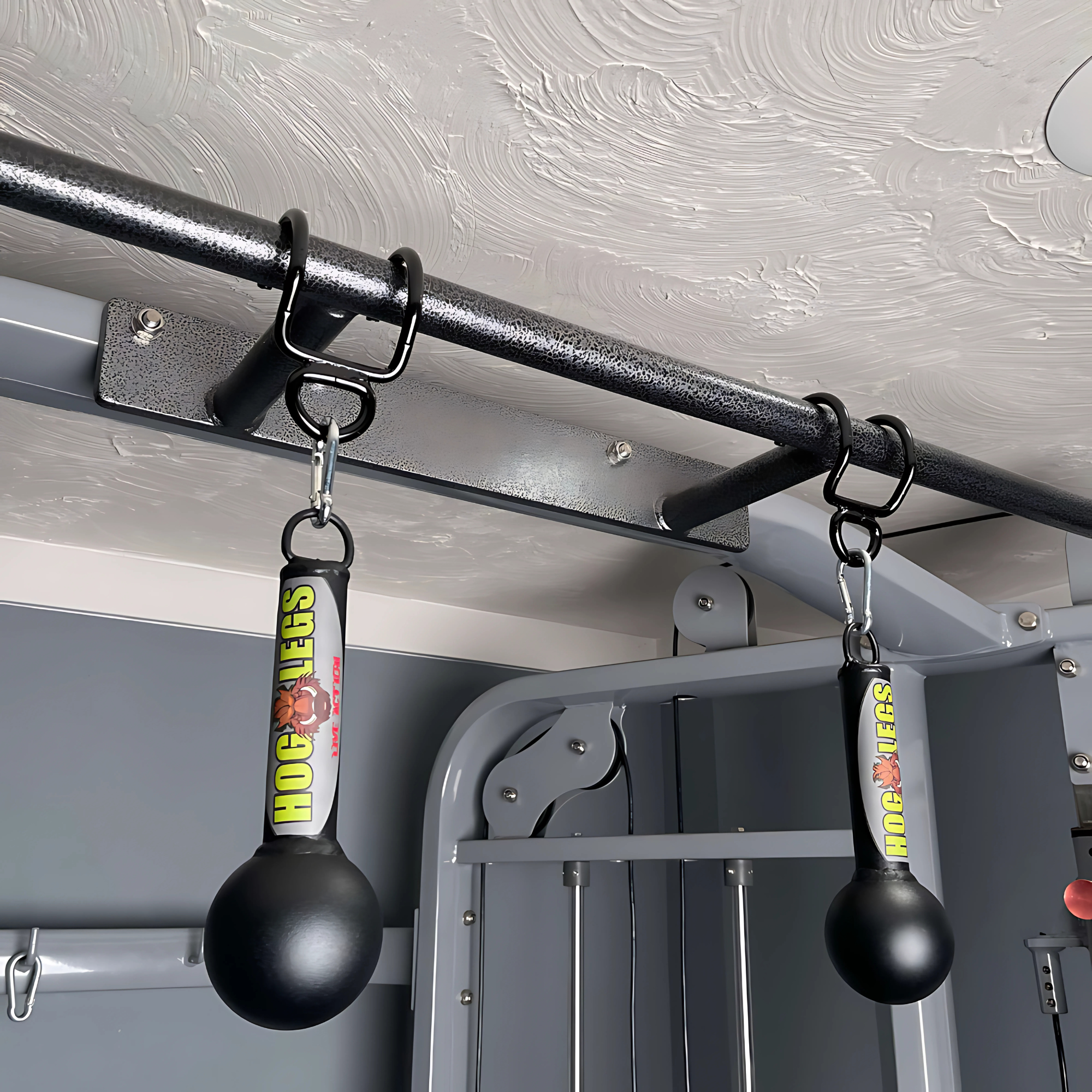 Two HOG LEGS 'Fist Full' Pullup Handles & Tricep Attachments hang from a metal pull-up bar in a home gym, ideal for extreme pull-ups and improving grip strength.