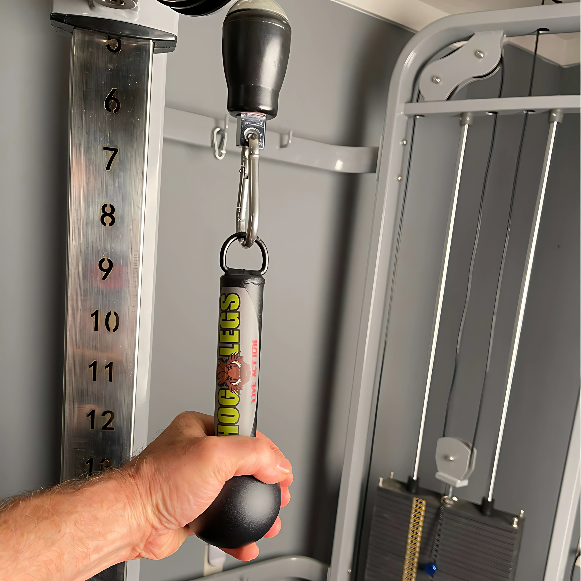 A hand grips the HOG LEGS 'Fist Full' Pullup Handles & Tricep Attachment, featuring a non-slip surface on a cable machine set to level 9, boosting grip strength during intense gym workouts.