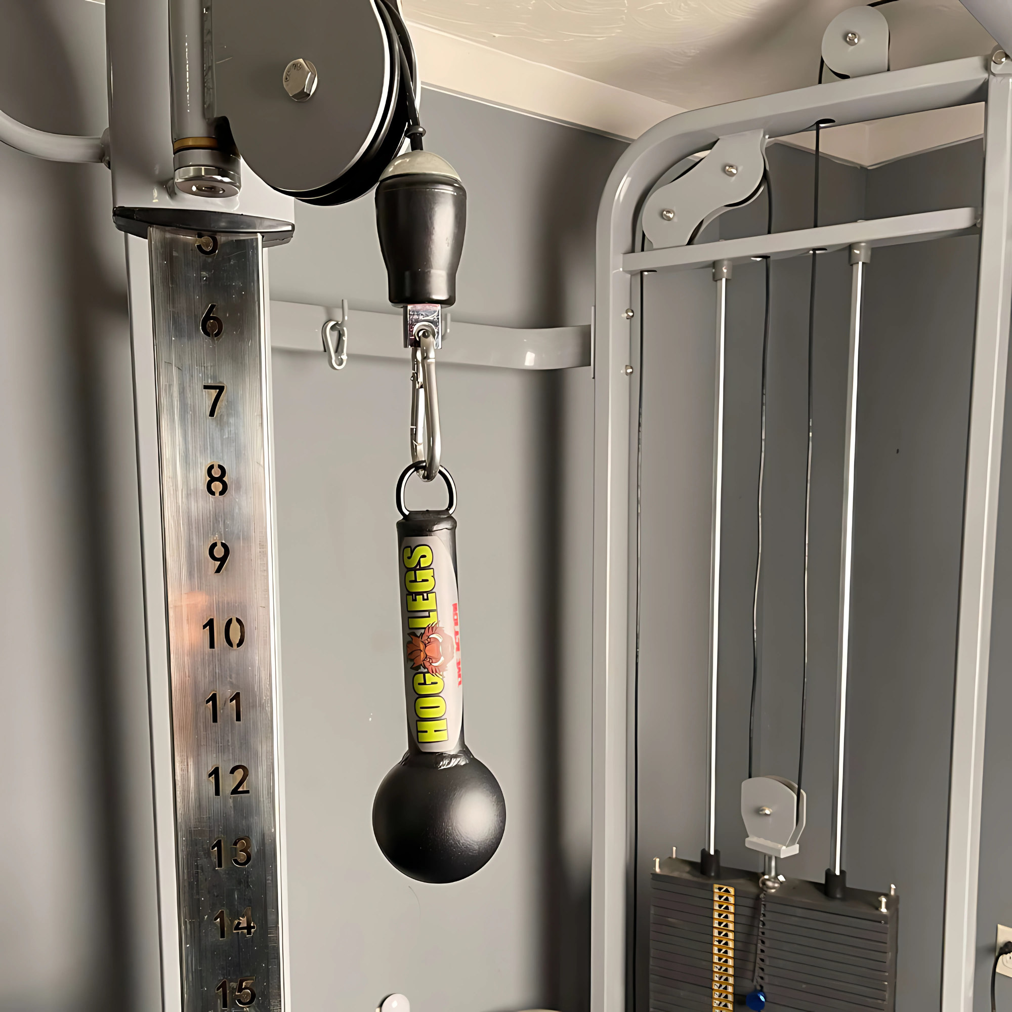 Close-up of a cable machine in a gym with HOG LEGS 'Fist Full' Pullup Handles & Tricep Attachment, ideal for grip strength training, and the weight stack visible.
