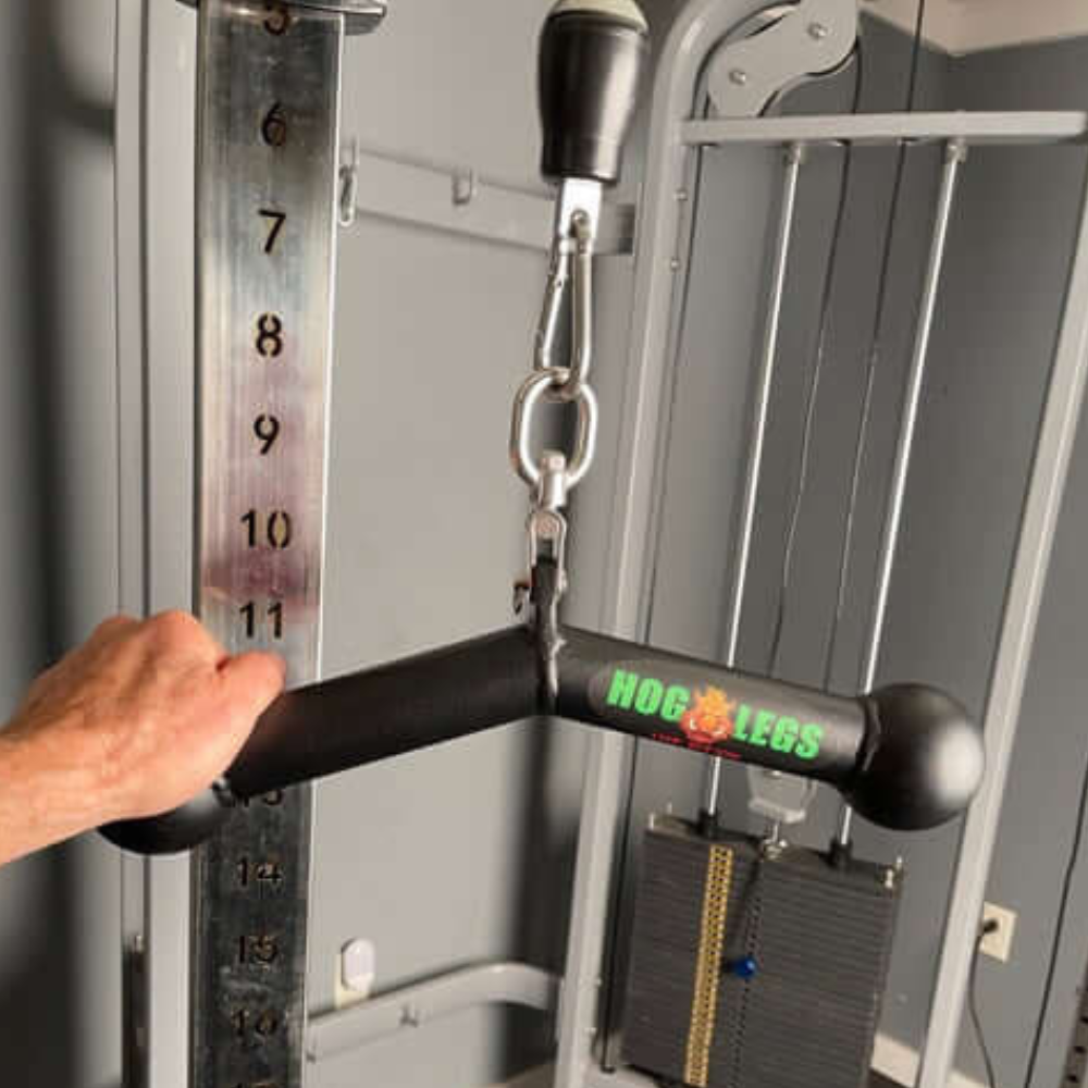 A hand grips the HOG LEGS 'Piglet Plus' Triceps Bar, known for its Balls of Steel, on a gym machine for optimized triceps targeting and muscle stimulation.