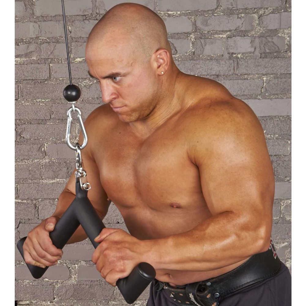 A person is intensely performing triceps extensions using the HOG LEGS 'Pork Chop' Killer Triceps Workout Cable Bar, set against a brick wall background.
