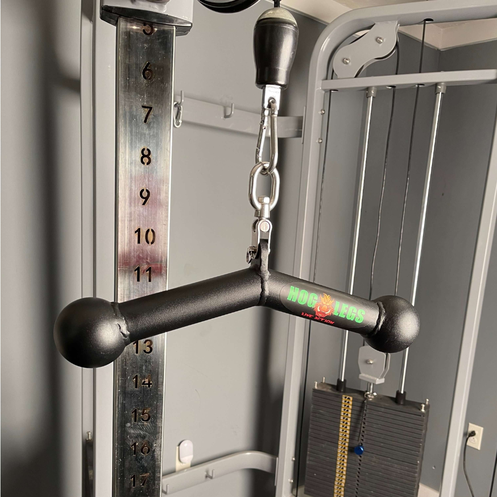 The HOG LEGS 'Piglet Plus' Triceps Bar with Balls of Steel is shown on an exercise machine with a weight stack in the background, crafted for optimal triceps targeting.