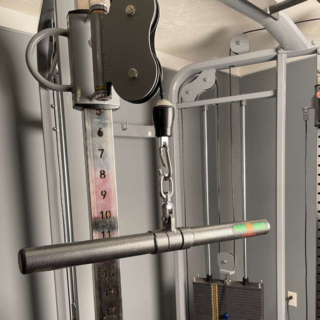 Close-up of the HOG LEGS 'Revolution' Fat Grip straight Curling Bar Gym Cable Attachment featuring a numbered weight stack and a black handlebar with powder coat gripping surface for enhanced muscle control.