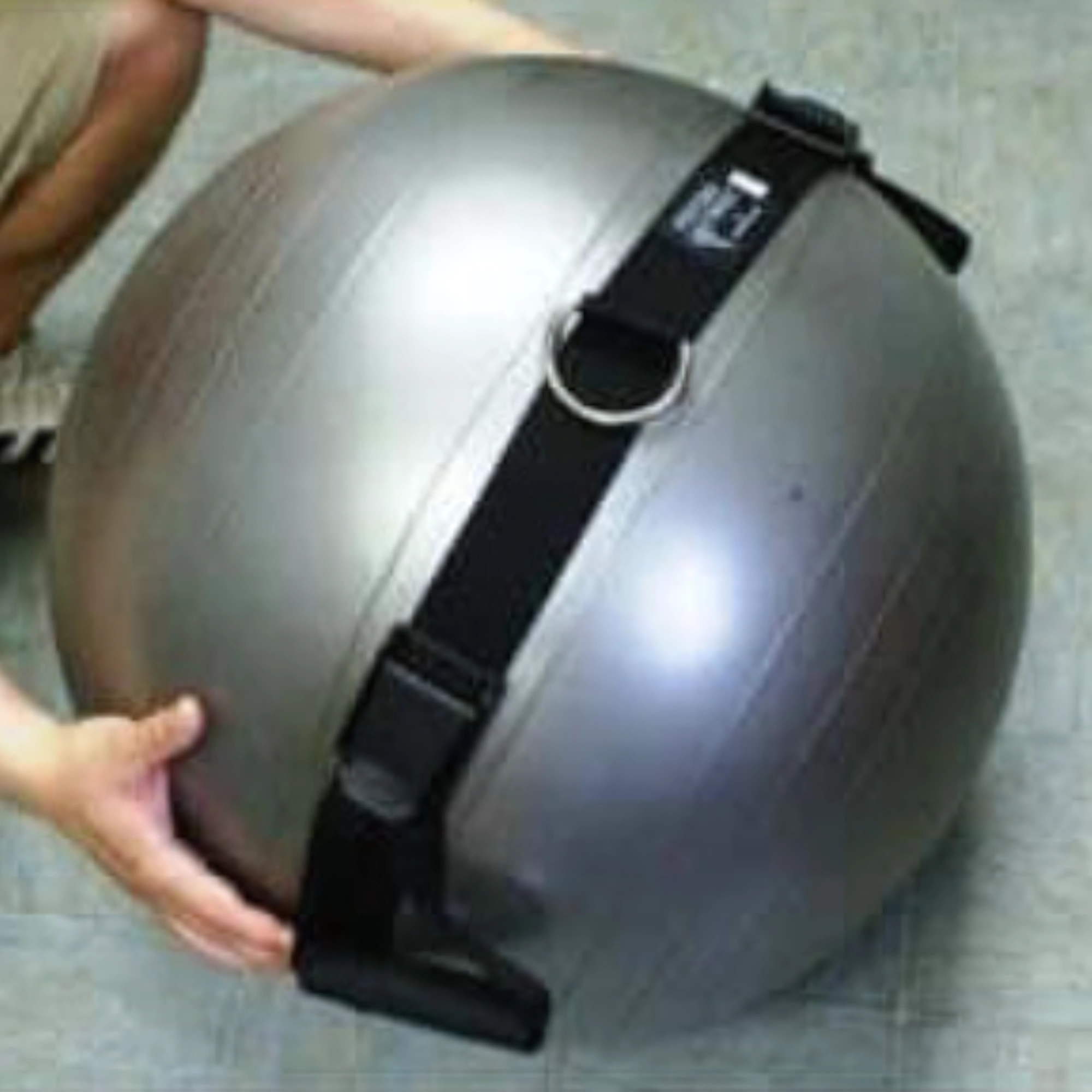 A person uses the PHYSIO TWIST Swiss Ball Handle Straps for Cable Machine Core—silver ball with a black strap and metal ring—ideal for explosive core workouts or Physio Twist routines alongside any cable machine weight stack.