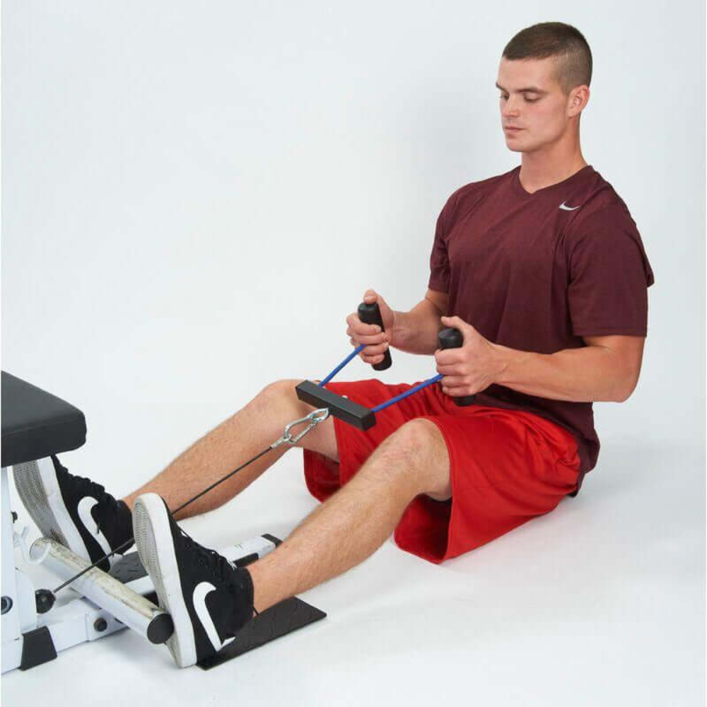 A person in a maroon shirt and red shorts is intensely exercising on a rowing machine, using the PULL FORCE 'Combo' T Bar & Seated Cable Row Alternative for enhanced strength training.