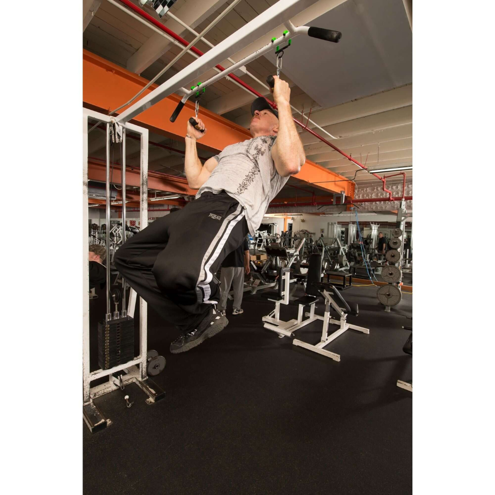 A man in the gym is doing pull-ups using the PULL FORCE 'Freestyle Motion' Rotating Pull Up Grips on a metal bar, amidst weightlifting equipment.