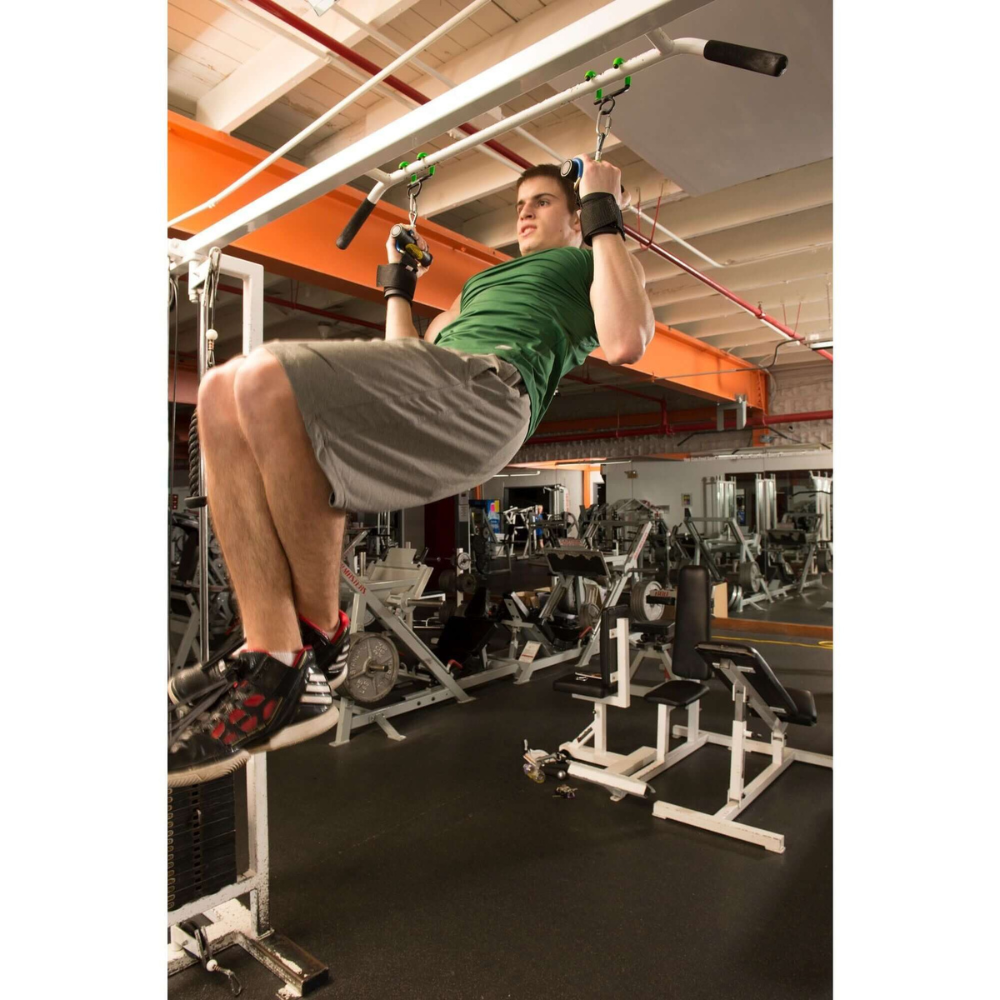 A man in a green shirt and gray shorts uses PULL FORCE 'Freestyle Motion' Rotating Pull Up Grips and wrist straps for support to perform pull-ups.