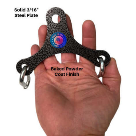A hand grips a black, triangular steel plate with rings and a handle attachment, featuring a blue "Made in USA" label, designed for Dual Cable machines; it's the PULL FORCE Mini Multiplier Home Gym Cable Machine Yoke.