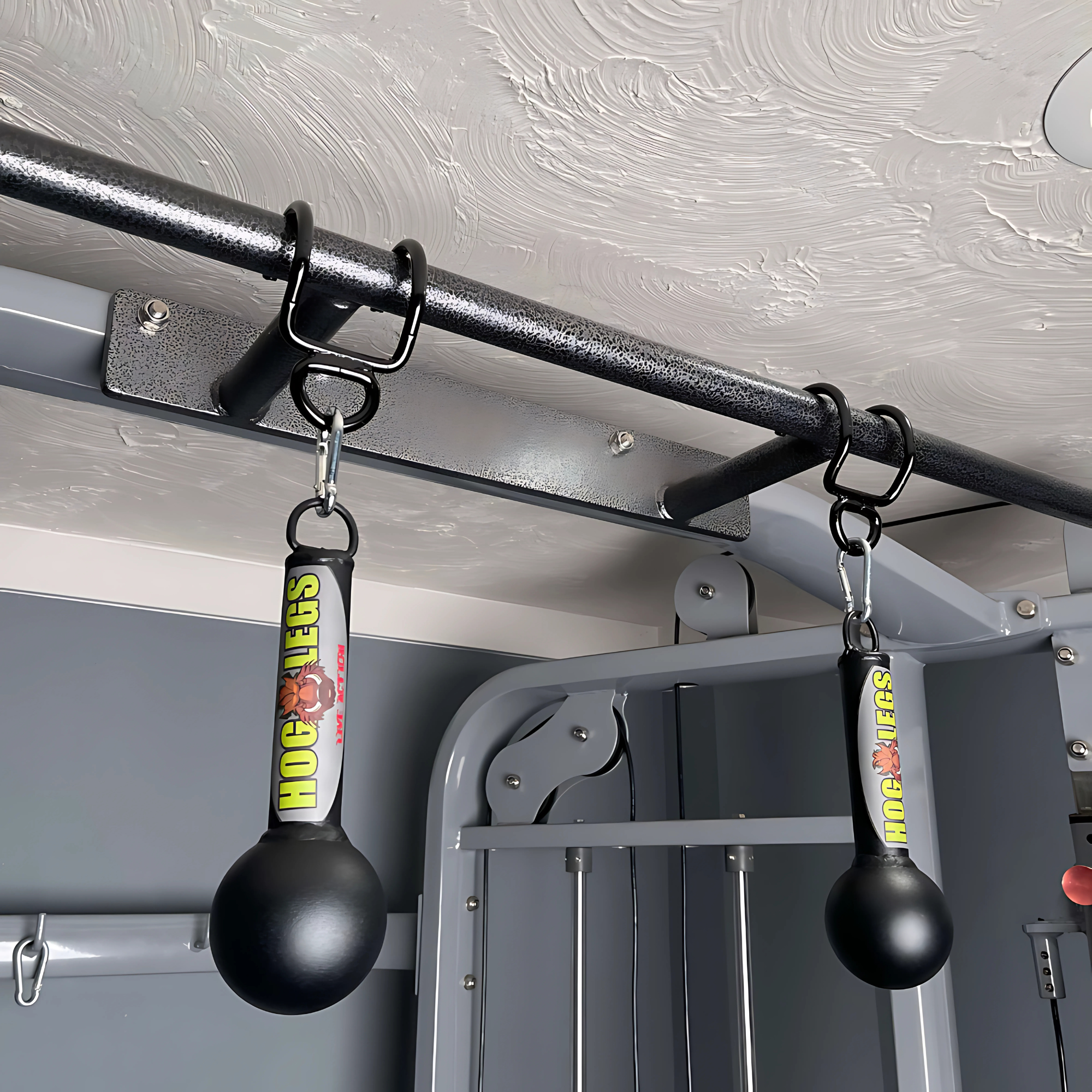 Two HOG LEGS grip trainers hang from the LPGmuscle PULL UP BAR WORKOUT 'Extreme pack', integrated into a home gym setup indoors.