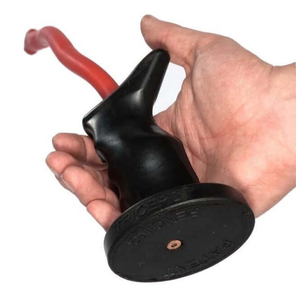 A hand grips a black rubber TACTI-TRICEPS tool with an ergonomic red handle, perfect for precise tricep exercises.