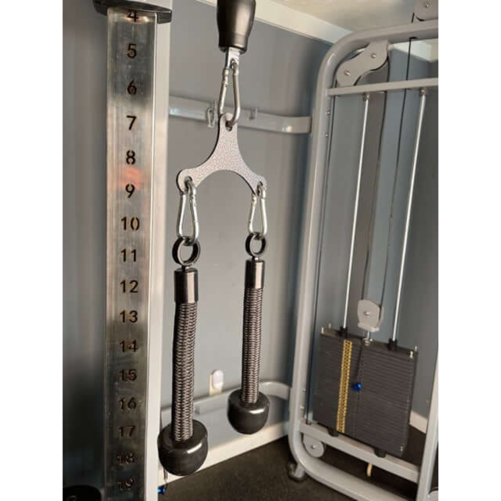 Close-up of gym cable machine with a TRD 'Dynamic Action' Yoke Triceps Attachment and weight stack showing numbers.