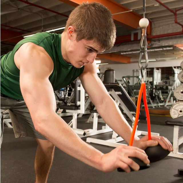 A man in a green shirt uses the TRICEPS TRIBULATION Cable Machine Attachment Set with handles connected to resistance bands at the gym.