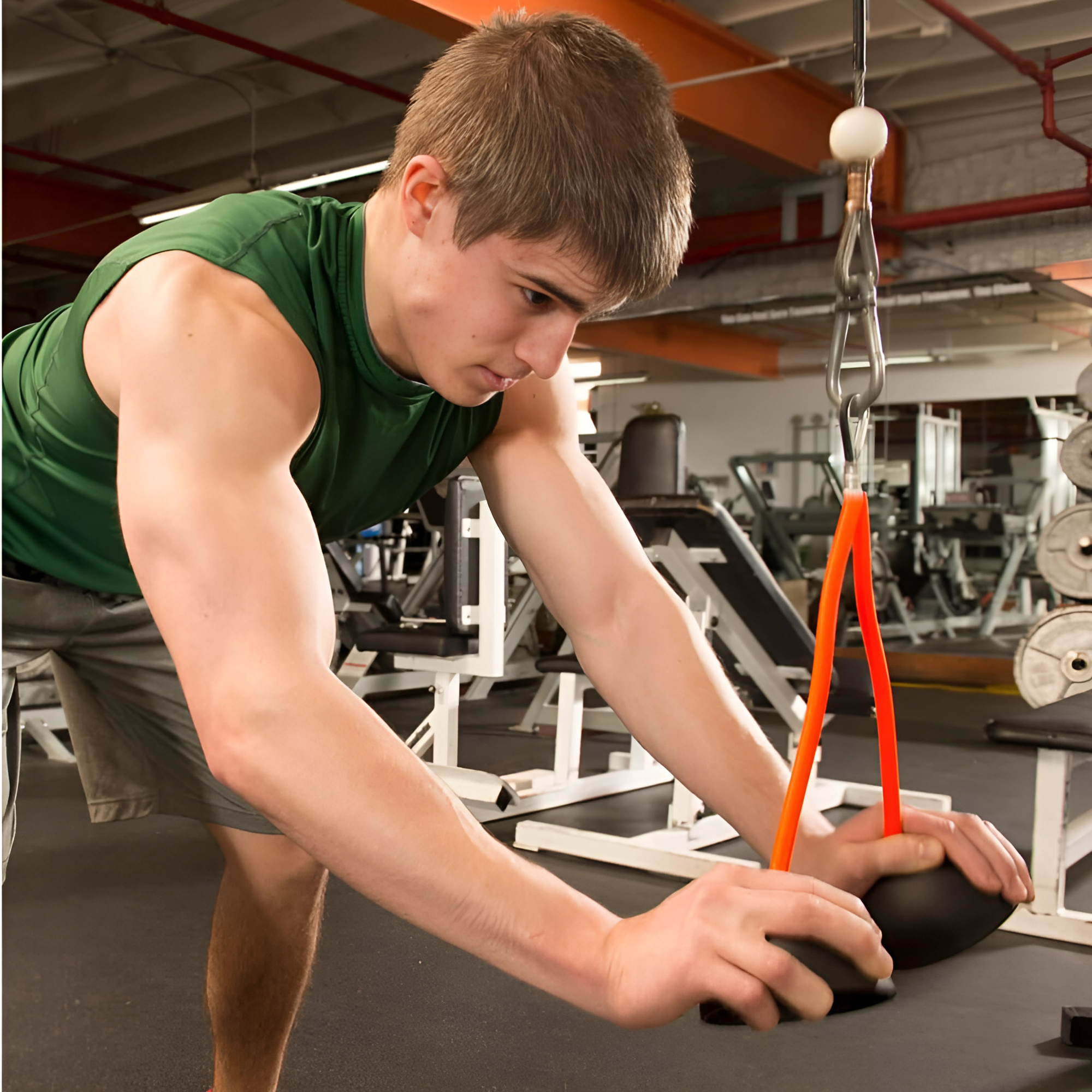 A young man works out in the gym using the TRICEPS TRIBULATION Cable Machine Attachment Set, focusing on triceps exercises to build strength and definition.